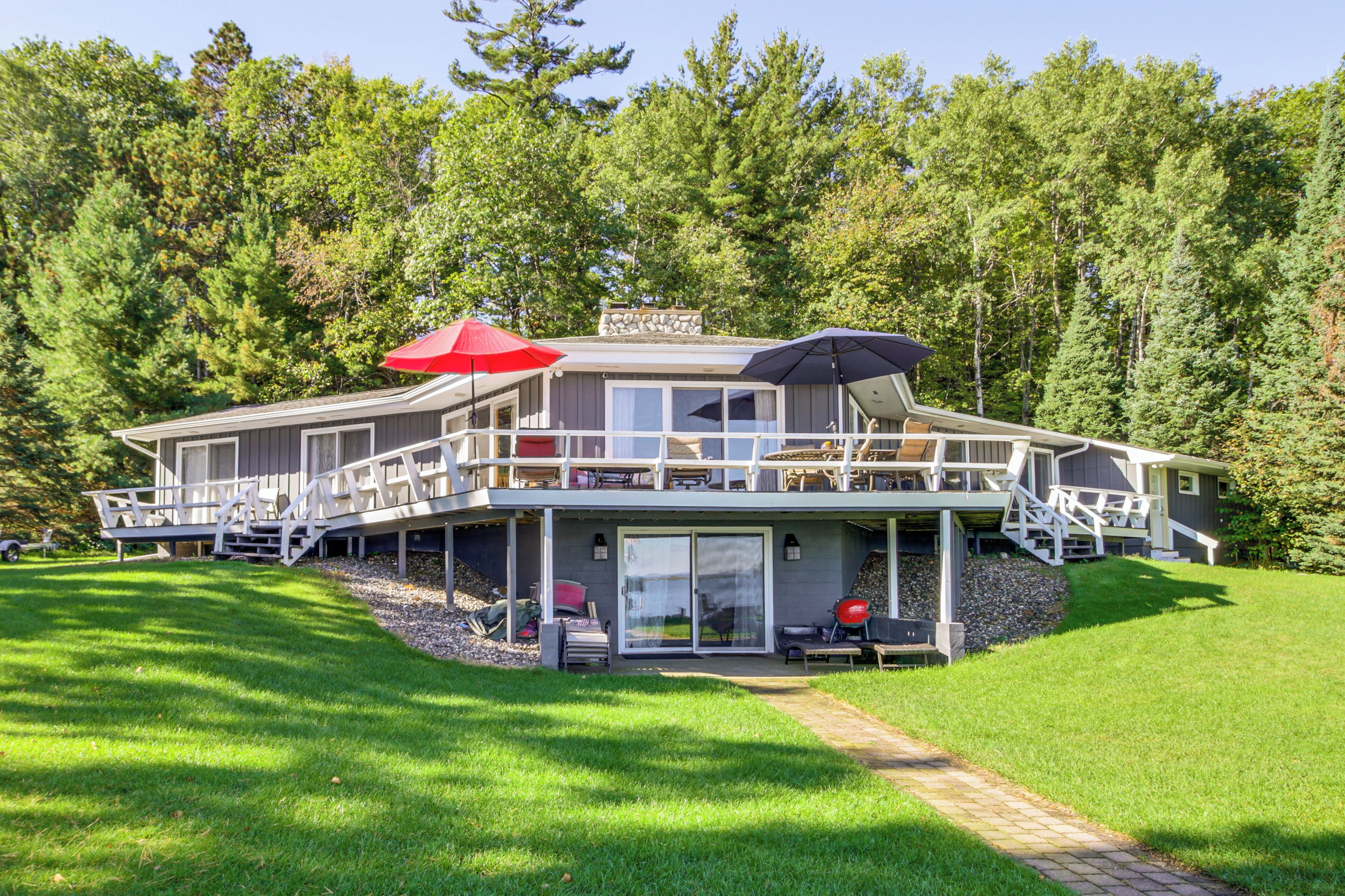 A two-story house with a balcony, a covered patio, and a stone foundation.