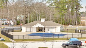 A fenced outdoor area with a building, a covered seating area, and a parking lot. - Bright Lewes Condo w/ Balcony, 7 Mi to Beach! (Lewes)