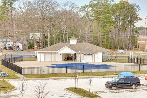 A fenced outdoor area with a building, a covered seating area, and a parking lot. - Bright Lewes Condo w/ Balcony, 7 Mi to Beach! (Lewes)