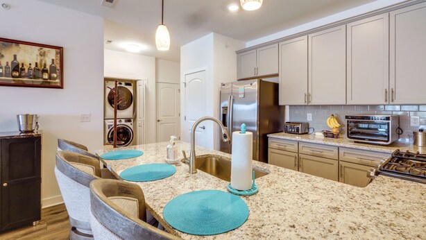 A modern kitchen with a granite countertop, stainless steel appliances, and teal placemats. - Bright Lewes Condo w/ Balcony, 7 Mi to Beach! (Lewes)