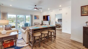 A spacious living area with a dining table, bar stools, a sofa, and a ceiling fan. - Bright Lewes Condo w/ Balcony, 7 Mi to Beach! (Lewes)