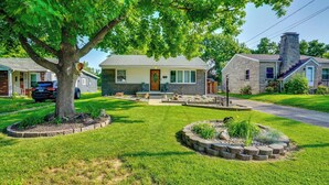 A single-story house with a stone chimney, a front yard with a tree, and a driveway. - Pet-friendly Clarksville Home w/ Central A/C (Clarksville)