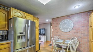 A kitchen with stainless steel appliances, wooden cabinets, a brick wall, and a round clock. - Pet-friendly Clarksville Home w/ Central A/C (Clarksville)