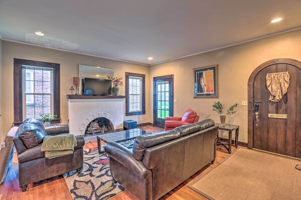 A living room with a fireplace, leather sofas, a coffee table, and a wooden door.
