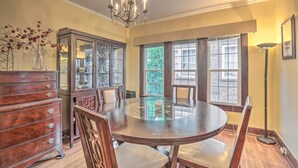 Une salle à manger avec une table ronde, des chaises en bois, un buffet et un lustre.