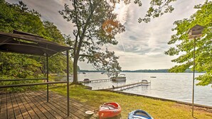 A wooden deck with kayaks and a paddle, overlooking a calm lake with boats and a dock. - 2 Mi to Winery: Le Roy Escape w/ Fire Pit & Views (Le Roy)