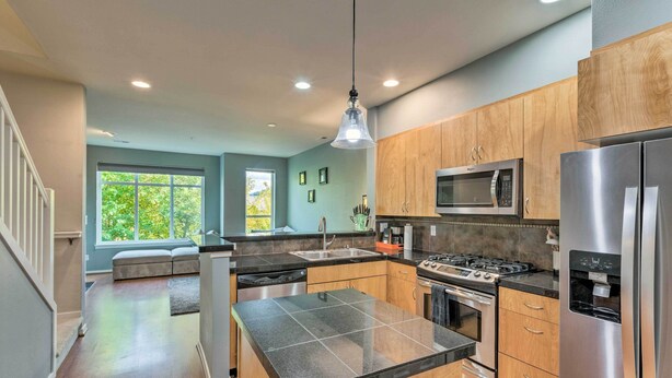 A modern kitchen with a central island, stainless steel appliances, and wooden cabinets. - Walk to Local Shops & Eats! Quaint Issaquah Home (Issaquah)