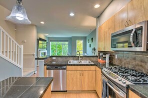 A modern kitchen with a stainless steel dishwasher, a gas stove, and a microwave. - Walk to Local Shops & Eats! Quaint Issaquah Home (Issaquah)