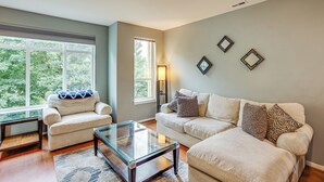 A living room with two sofas, a glass coffee table, and a large window offering a view of trees. - Walk to Local Shops & Eats! Quaint Issaquah Home (Issaquah)