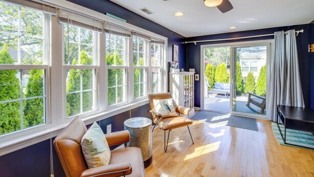 A spacious room with large windows, a ceiling fan, and a view of greenery outside. - Cape May Quad w/ Grill - 7 Blocks to Beach! (Cape May)
