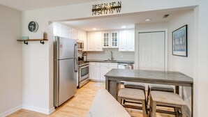 A modern kitchen with white cabinets, a stainless steel refrigerator, and a wooden island with bar stools. - Cape May Quad w/ Grill - 7 Blocks to Beach! (Cape May)