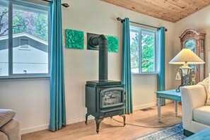 A cozy living room with a black wood-burning stove, a vintage clock, and a blue table lamp.