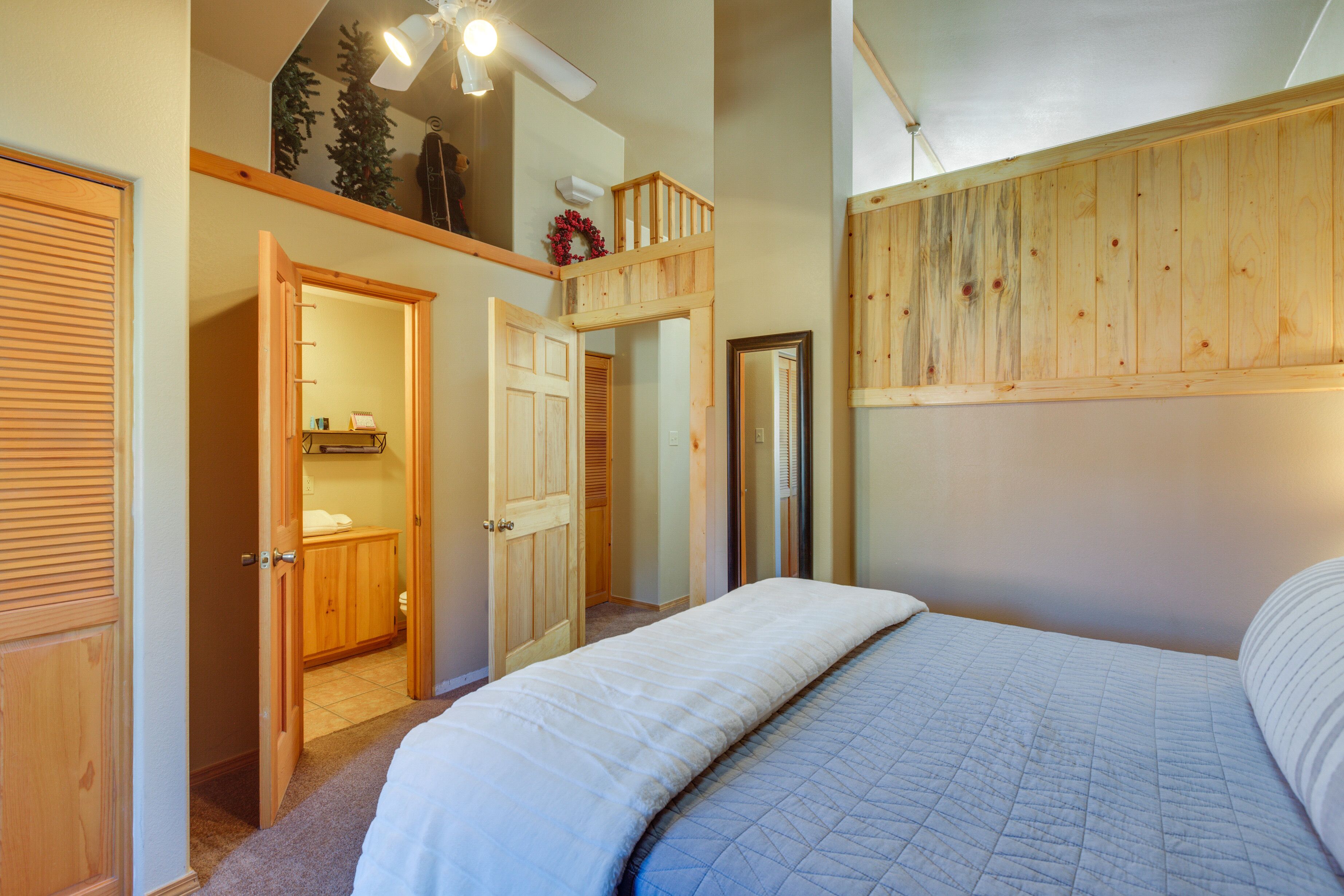 A bedroom with a bed, wooden wardrobe, and a ceiling fan.