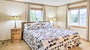 A bedroom with a large bed, two bedside tables with lamps, and a window with curtains.