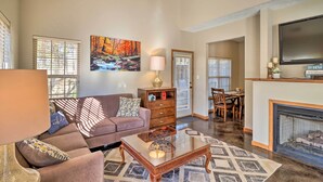 A spacious living room with a sofa, coffee table, and fireplace. There is a painting on the wall and a television mounted above the fireplace. - Heber Springs Cabin ~ 1 Mi to Sugarloaf Mtn! (Heber Springs)