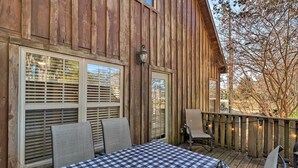 A wooden deck with a checkered table and chairs, large windows with blinds, and a string of lights. - Heber Springs Cabin ~ 1 Mi to Sugarloaf Mtn! (Heber Springs)