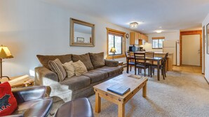 A living room with a sofa, coffee table, and a dining area with chairs and a table.