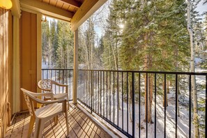 Eine Holzterrasse mit Geländer, mit Blick auf einen verschneiten Wald.