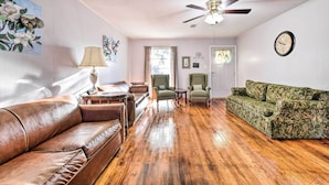 A spacious living room with a brown leather couch, a green floral sofa, and a wooden floor. - Outdoor Dining & Yard: Pet-friendly Temple Home (Temple)