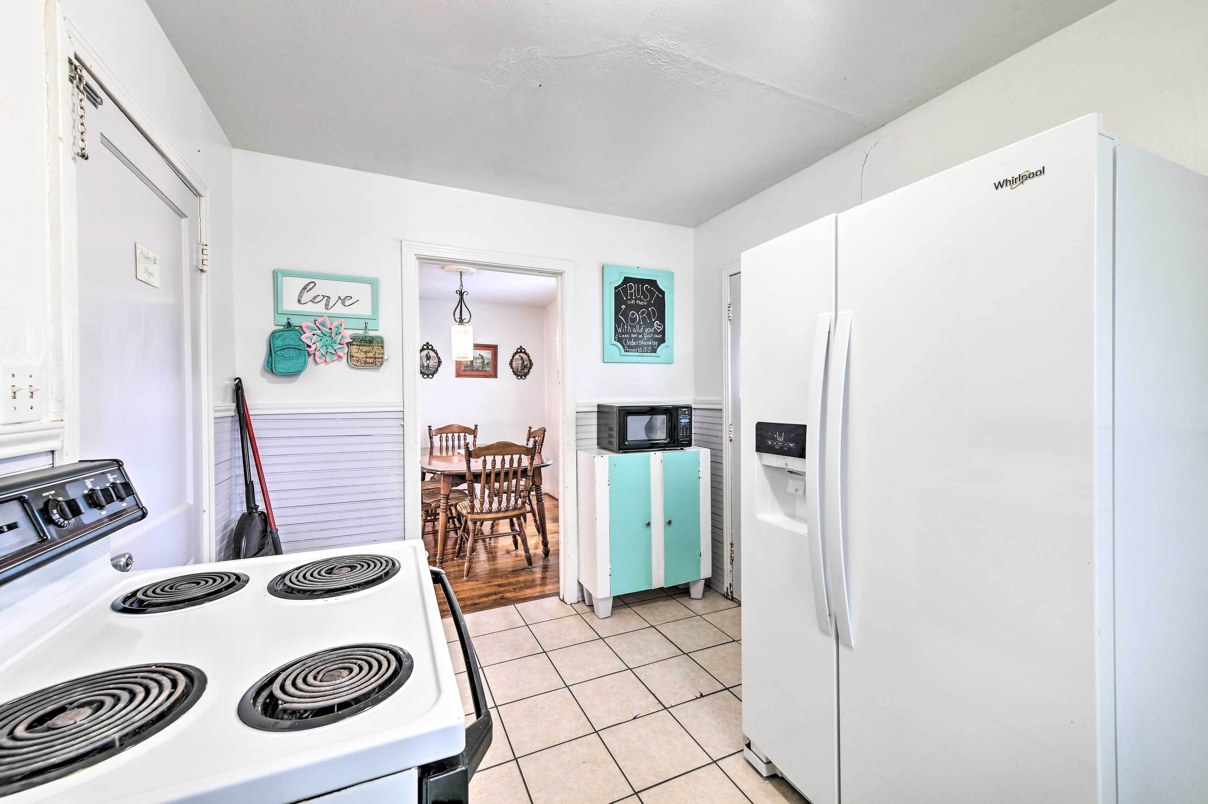 A kitchen with a white stove, a white refrigerator, and a teal cabinet.