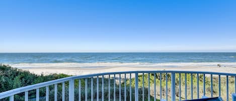 A balcony with a view of the beach and ocean.
