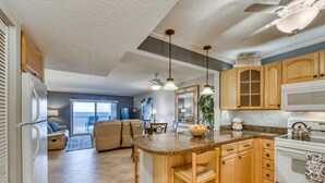 A kitchen with wooden cabinets, a granite countertop, and a built-in oven. - Oceanfront- Heated Pool-Balcony (Indialantic)