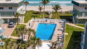 A pool with a view of the ocean, surrounded by palm trees and a beach. - Oceanfront- Heated Pool-Balcony (Indialantic)