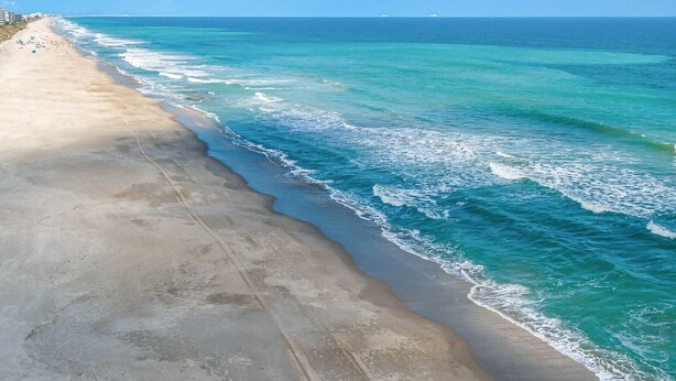 A beach with a wide sandy shore and gentle waves. - Oceanfront- Heated Pool-Balcony (Indialantic)