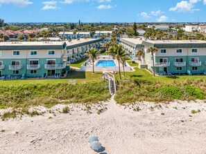 A beachfront hotel with multiple-story buildings, a swimming pool, and a sandy beach path leading to the pool. - Oceanfront- Heated Pool-Balcony (Indialantic)