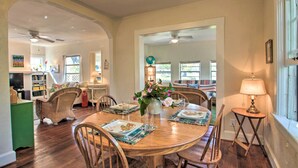 A dining area with a round table, chairs, and a vase with flowers. There is a lamp on a side table and a bookshelf in the background. - Colorful Pensacola Oasis: 1 Block to Bayview Park! (Pensacola)