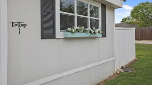 A white building with black shutters, a window with a flower box, and a sign reading "trotage". - Boat & Fish on Lewisville Lake: Pet-friendly Haven (Lake Dallas)