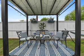 An outdoor patio with a covered seating area, a decorative wreath, and string lights.