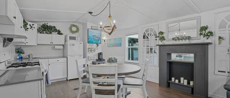 A kitchen with white cabinets, a round dining table, and a chandelier.