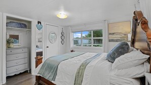 A bedroom with a bed, a dresser, a vanity, and a window with a view of greenery. - Boat & Fish on Lewisville Lake: Pet-friendly Haven (Lake Dallas)
