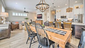 A spacious dining area with a wooden table and chairs, a chandelier, and a kitchen in the background. - 7 Mi to Disney: Reunion Resort Oasis w/ Pool (Kissimmee)