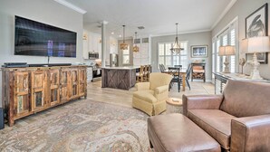 A spacious living room with a large TV, a wooden cabinet, a patterned rug, and a leather sofa. - 7 Mi to Disney: Reunion Resort Oasis w/ Pool (Kissimmee)