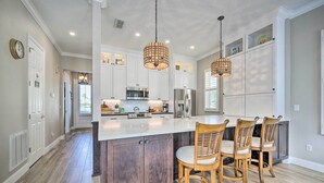 A spacious kitchen with a large island, wooden chairs, and pendant lighting. - 7 Mi to Disney: Reunion Resort Oasis w/ Pool (Kissimmee)