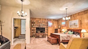 A cozy room with a bed, a wooden bookshelf, a television, and a leather sofa. - Charming Aiken Vacation Rental 2 Mi to Dtwn! (Aiken)