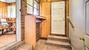 A wooden interior with a staircase leading to a white door, a small seating area with patterned chairs, and a brick wall. - Charming Aiken Vacation Rental 2 Mi to Dtwn! (Aiken)