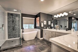 Une salle de bain moderne dotée d’une douche à parois de verre, d’une baignoire sur pieds et d’un meuble-lavabo avec un grand miroir.