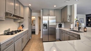 Una cocina moderna con armarios grises, un refrigerador de acero inoxidable y una encimera de mármol.