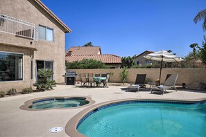 Un jardin à l’arrière d’une maison, avec une piscine, du mobilier d’extérieur et un espace patio.