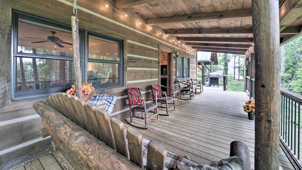 Eine Holzterrasse mit Schaukelstühlen und einer Bank, einem Deckenventilator und Lichterketten.