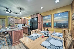 Eine Küche mit Holzschränken, einem schwarzen Kühlschrank und einem Essbereich mit einem Holztisch, gedeckt für vier Personen.