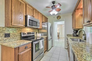 A kitchen with wooden cabinets, stainless steel appliances, granite countertops, and a ceiling fan. - Pet-friendly Home Close to WEC Ocala! (Ocala)