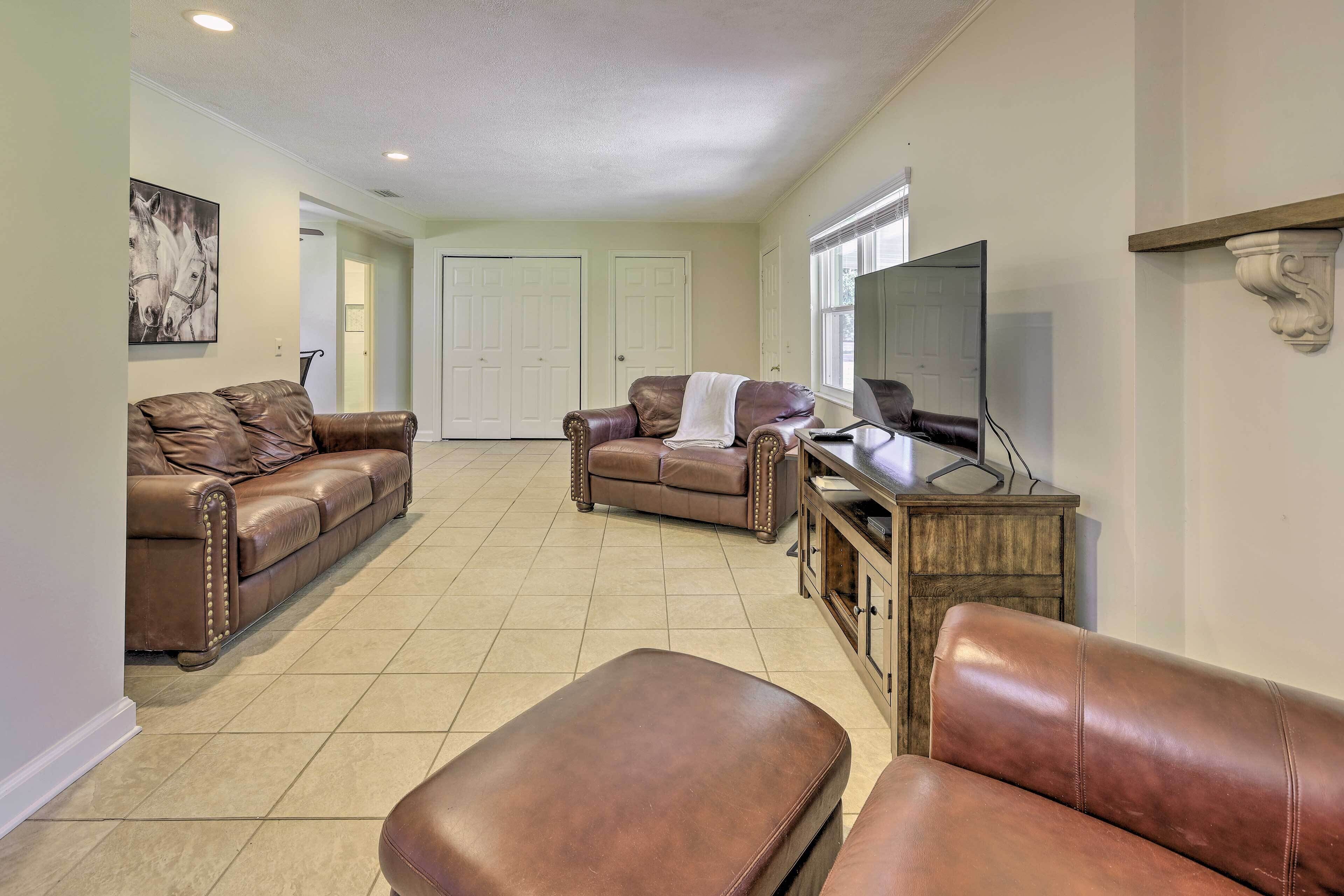A spacious living room with two brown leather sofas, a wooden cabinet, and a television.