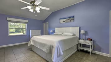 A bedroom with a bed, a nightstand, a ceiling fan, a window, and a wall clock.