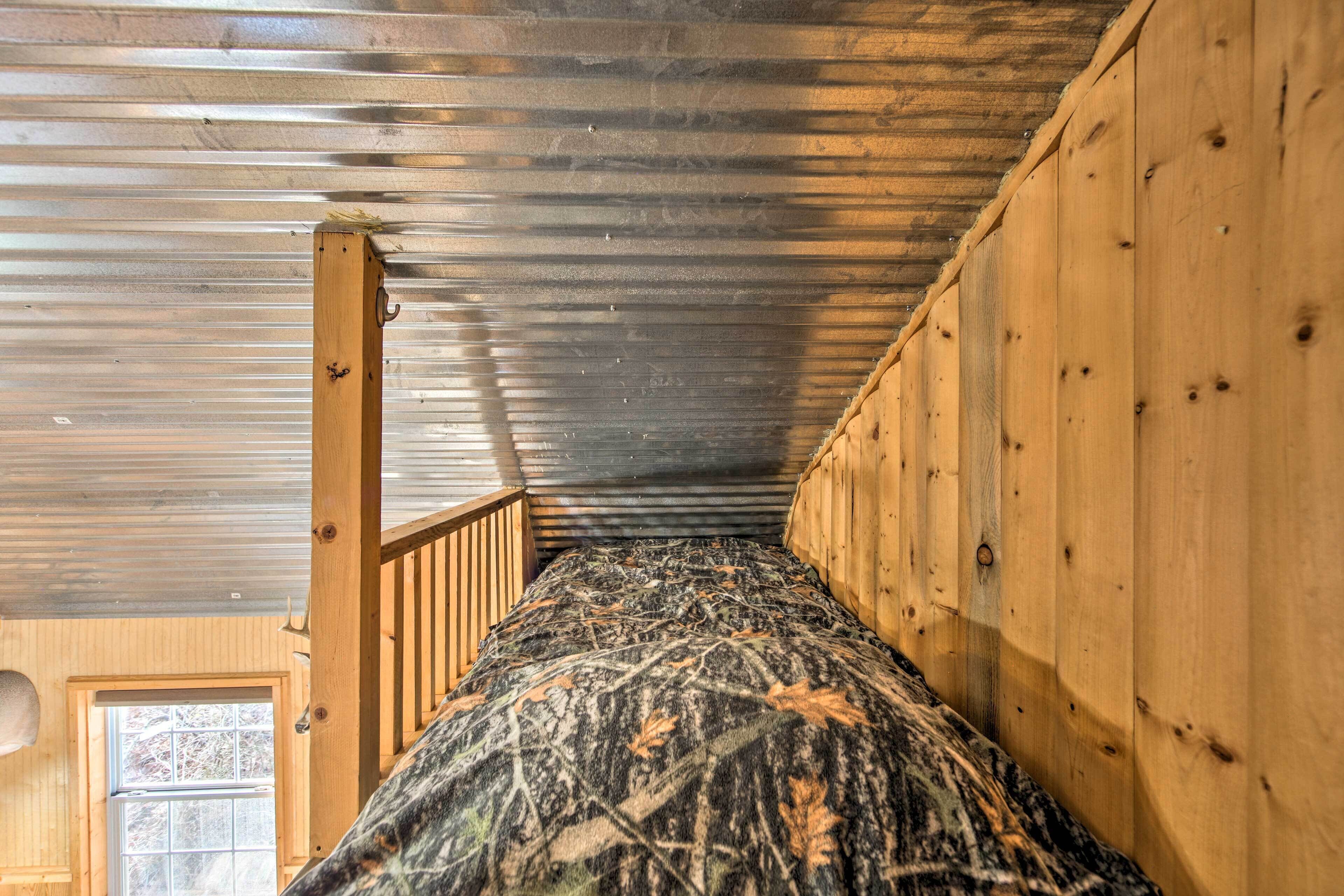 Un lit superposé avec un matelas à motifs de camouflage, des barreaux en bois et un plafond en métal.