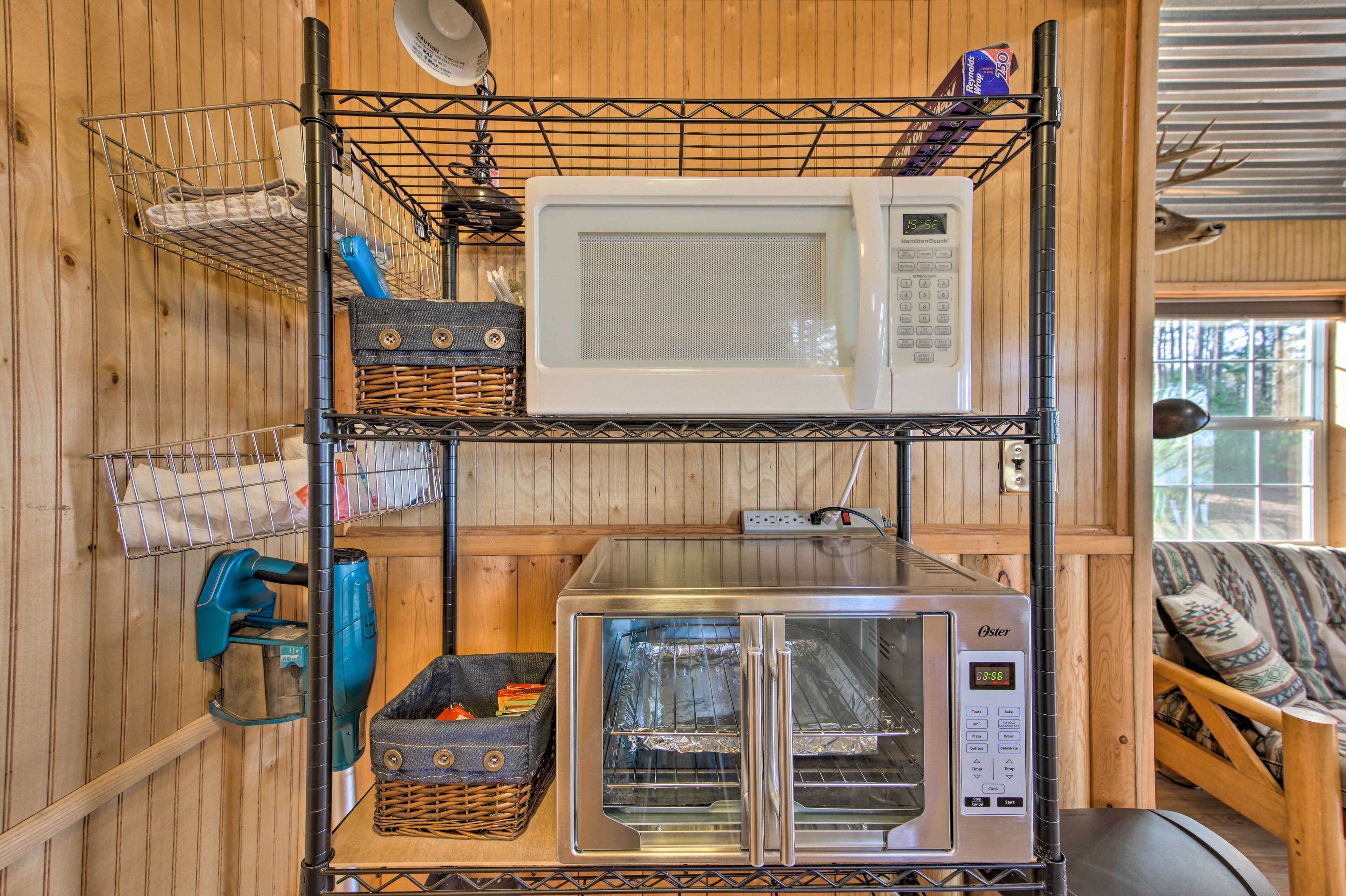 A kitchen with a microwave, toaster, and oven on a wooden wall shelf.