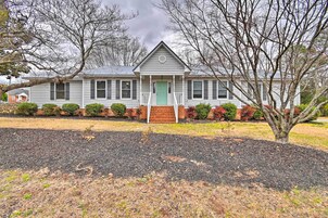 A two-story house with a front porch, a green door, and a brick foundation.